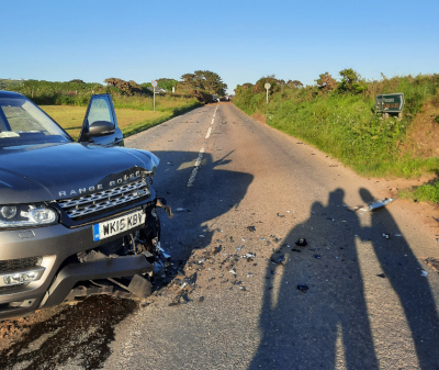 Photo of the aftermath of Guy's car accident. A damaged Land Rover lies in the road on the left of the photo.